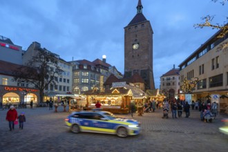 Christmas market, winter night at Jakobsplatz, behind White Tower, in front a passing police car,