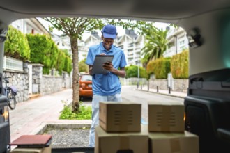 Delivery african young man doing paperwork before deliver parcels on a van