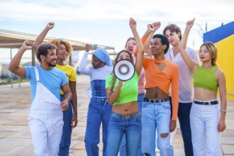 Multicultural and gender diverse young people yelling using a loudspeaker in a protest on an urban