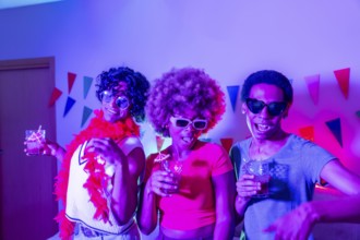 Multiracial friends partying at home at night with colorful neon light illuminating the apartment