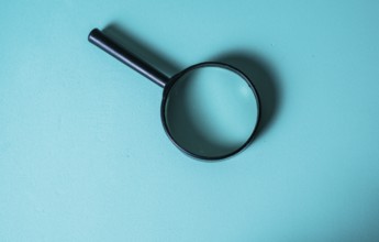 Magnifying Glass on Teal Background for Investigation Concept. CloseUp of Magnifying Glass for