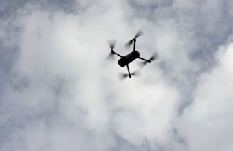 Silhouette of a drone in flight backlit against the sky, Switzerland