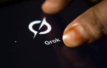 In this photo Illustration a person taps Grok AI application icon on a tablet device on 24 May 2025