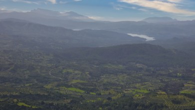 Sky exchanged, Sweeping view of a hilly, green landscape with mountains in the background under a