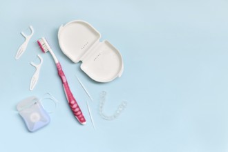 Top view of dental clear aligners, toothbrush, toothpicks and floss on blue background with copy