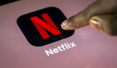 In this photo Illustration a person taps Netflix App icon on a tablet device on 24 May 2025 in New