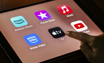 In this photo Illustration a person taps apple TV app icons on a tablet device on 24 May 2025 in