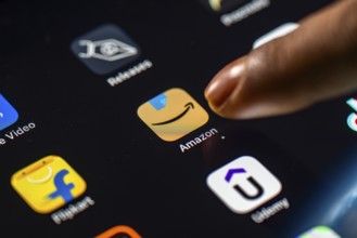 In this photo Illustration a person taps Amazon shopping app icon on a tablet device on 24 May 2025