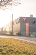 Tesla production facility in the sunset with grey building and modern logo, Tesla, Holzgerlingen,