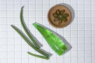 Aloe vera leaves and a container of aloe gel arranged on white bathroom tiles, symbolizing natural