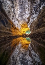 Lava tunnel, illuminated lava cave with perfect reflection in an underground lake, Cueva de los
