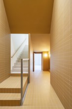 A modern staircase and hallway showcase sustainable architecture with vibrant orange and cream