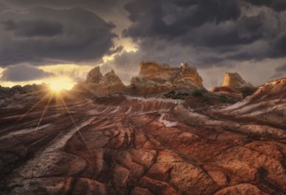 A dramatic sunset casts golden light over a rugged desert landscape, highlighting the textures of
