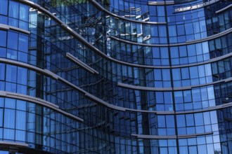 A close-up view of a modern building showcasing a curved glass facade with visible reflections and