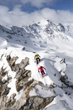 Two mountaineers climbing the narrow ridge of Piz Laviner, view of mountain panorama in winter