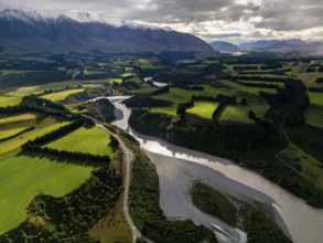 Aerial view of Canterbury region's lush green farmland and winding river, nestled against the