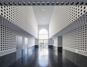 Auditorium hallway with intricate geometric wall patterns and glossy reflective floor, leading to a