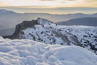 Scenic view of Montcabrer, Spain, showcasing its snow-covered peaks under a softly glowing sunrise.