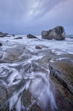 Rocks on beach of fjord of Norwegian sea in winter on sunset. Utakliev beach, Lofoten islands,