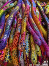 A vibrant collection of colorful plush snakes displayed in a Thai souvenir market. Each snake