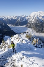 Tourist with camera on a hiking trail, Snow-covered summit of the Jenner with viewing platform in