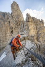 Mountaineer climbs an exposed rock in the secured Via Ferrata Bocciere Centrale via ferrata,