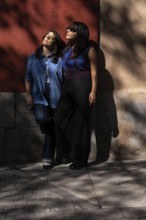 A multiethnic lesbian couple shares an intimate moment outdoors, exuding warmth and unity. The