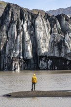 Tourist at the lakeside of a glacier lagoon, glacier tongue with crevasses and lake,
