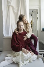 Two siblings share a tender moment indoors, capturing the warmth of family bonds Natural light
