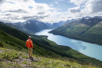 Mountaineer enjoys views of blue lake and mountains on Twin Peaks Trail, Eklutna Lake, Chugach
