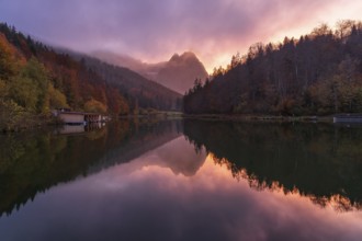 A stunning sunset at Riessersee in the Bavarian Alps casts vivid colors over calm waters,