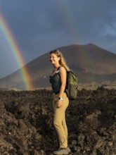 A woman stands amidst volcanic terrain at Timanfaya National Park, Lanzarote, enjoying a vibrant