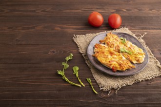 Baked chicken meat with cheese and tomatoes on brown wooden background and linen textile. side