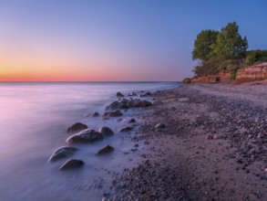 Unspoiled secluded stretch of coast with cliffs and boulders in the evening light on the Baltic Sea