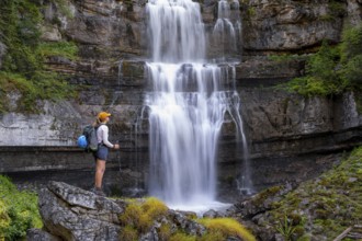 Young pretty hiker standing on rocks in front of Cascata di Mezzo waterfall, long exposure,