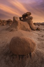 Dramatic sandstone formations under a vibrant sunset sky in Goblin Valley State Park, Utah, USA.