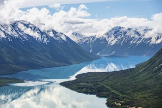 View of snowy mountains in spring and turquoise Kenai Lake with reflection, Slaughter Ridge Trail,