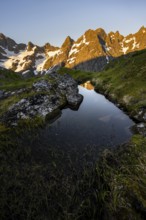 Rocky mountain peaks with reflection, small pond in moor landscape at Trollfjord Hytta, mountain
