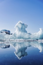 A majestic ice formation towers over the serene waters of Glacier Jokulsarlon in Iceland,