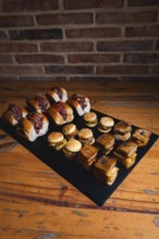 A selection of gourmet sliders and assorted bites arranged on a wooden table. The image captures an