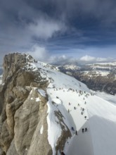 View of the snow-covered Marmolta (3343 m) with skiers in the foreground and clouds in the