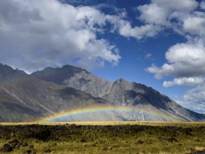A stunning autumn scene at Mount Cook, New Zealand, showcasing a vibrant rainbow arching over lush