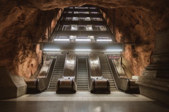 View of escalators at a Stockholm subway station, surrounded by cave-like rock formations. The