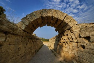 Crypt, vaulted walkway to the stadium, old stone arch leading through massive walls under a blue