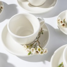 From above a collection of pristine white cups arranged with delicate spring blossom branches on a