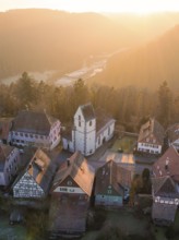 Half-timbered houses and a church in warm sunset light look idyllic and peaceful, Zavelstein, Calw