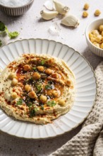 A delicious hummus dish is presented on a decorative plate, topped with chickpeas, sesame seeds,