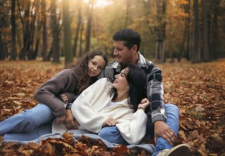 A joyful family relaxes in a forest amidst colorful autumn leaves. The warm tones and soft light