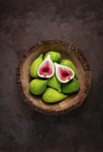 Fresh green figs, in a wooden plate, top view, close-up, no people