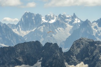 A lone paraglider glides gracefully above the rugged peaks of the French Alps near Chamonix and